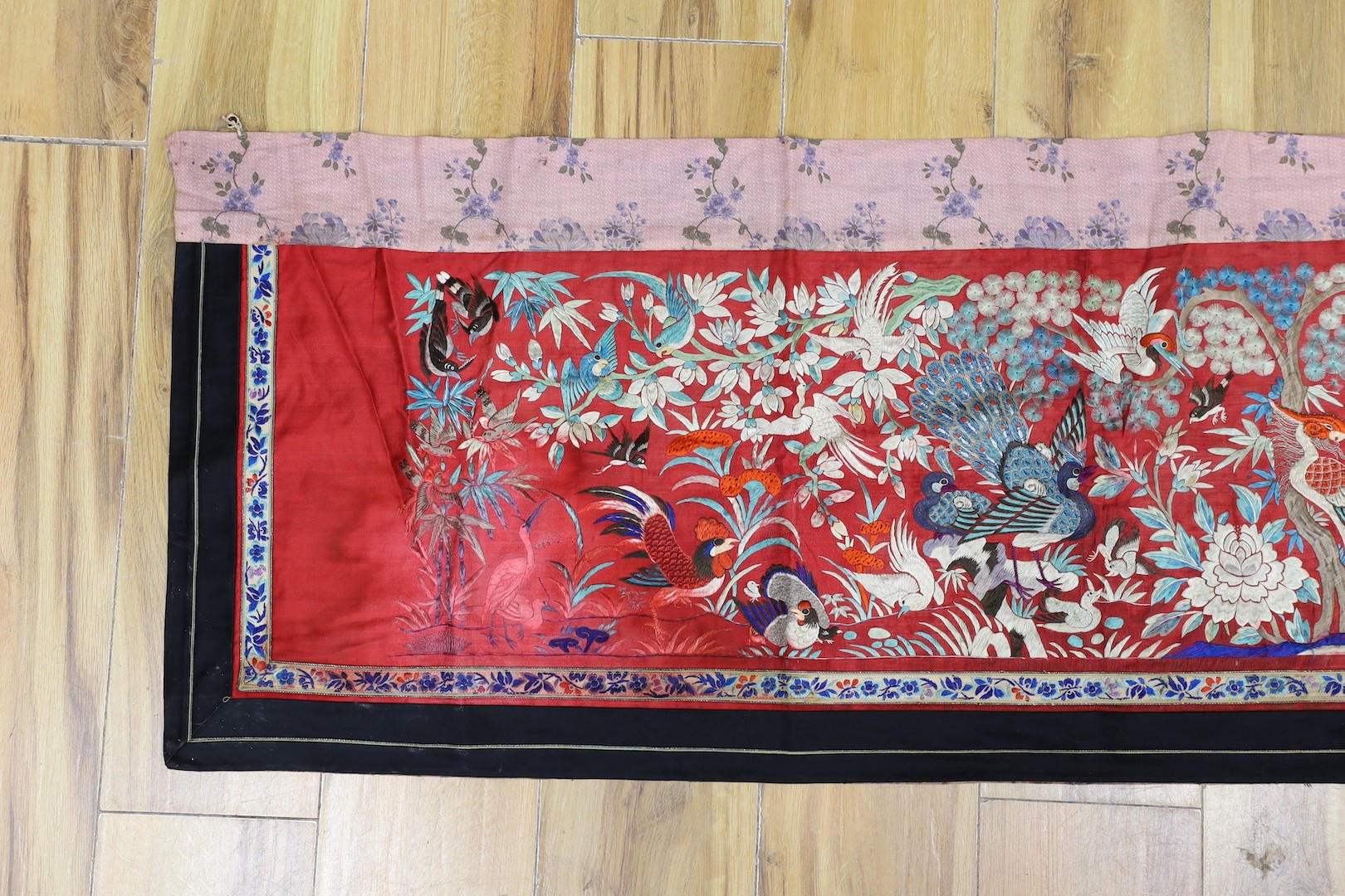 An early 20th century Chinese embroidered silk helmet multi coloured embroidery on a red background depicting oriental birds. 183cm x 47.5cm. 183cm x 47.5cm